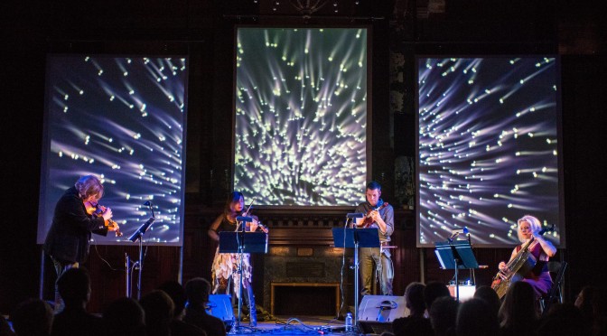 ETHEL performing with illuminated screens behind them