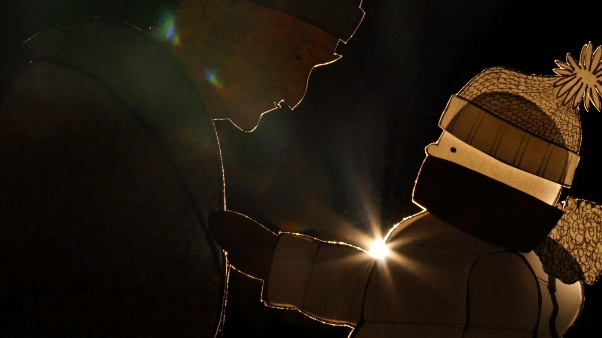 Two figures, likely an adult and a child in winter clothing and hats, are silhouetted against a dark background with a bright light shining between them, creating a warm glow and lens flare.