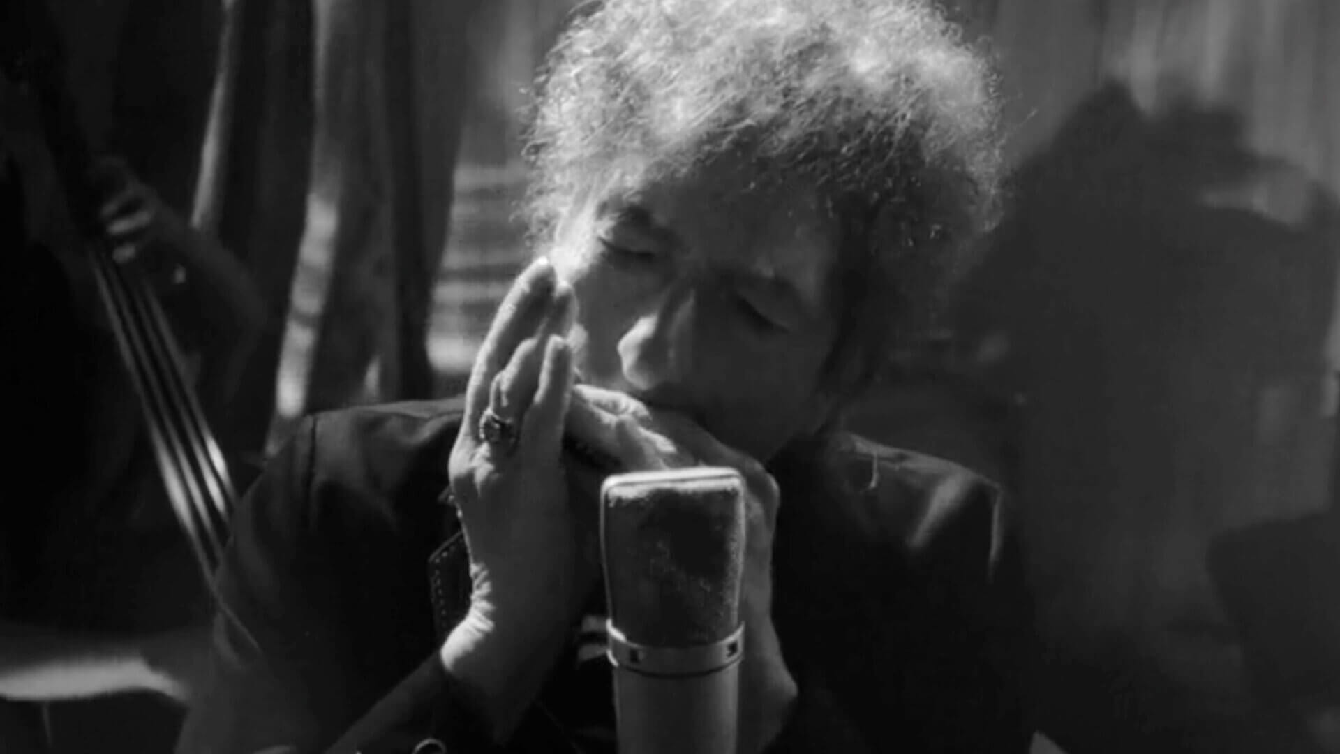 Black and white photo of Bob Dylan playing harmonica