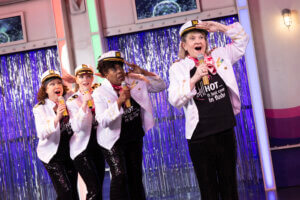 Menopause 2 cast singing in sailor uniforms