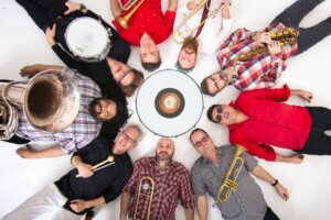 Members of Slavic Soul Party lying down in a circular formation holding instruments