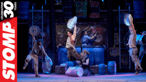 STOMP performers on stage with logo