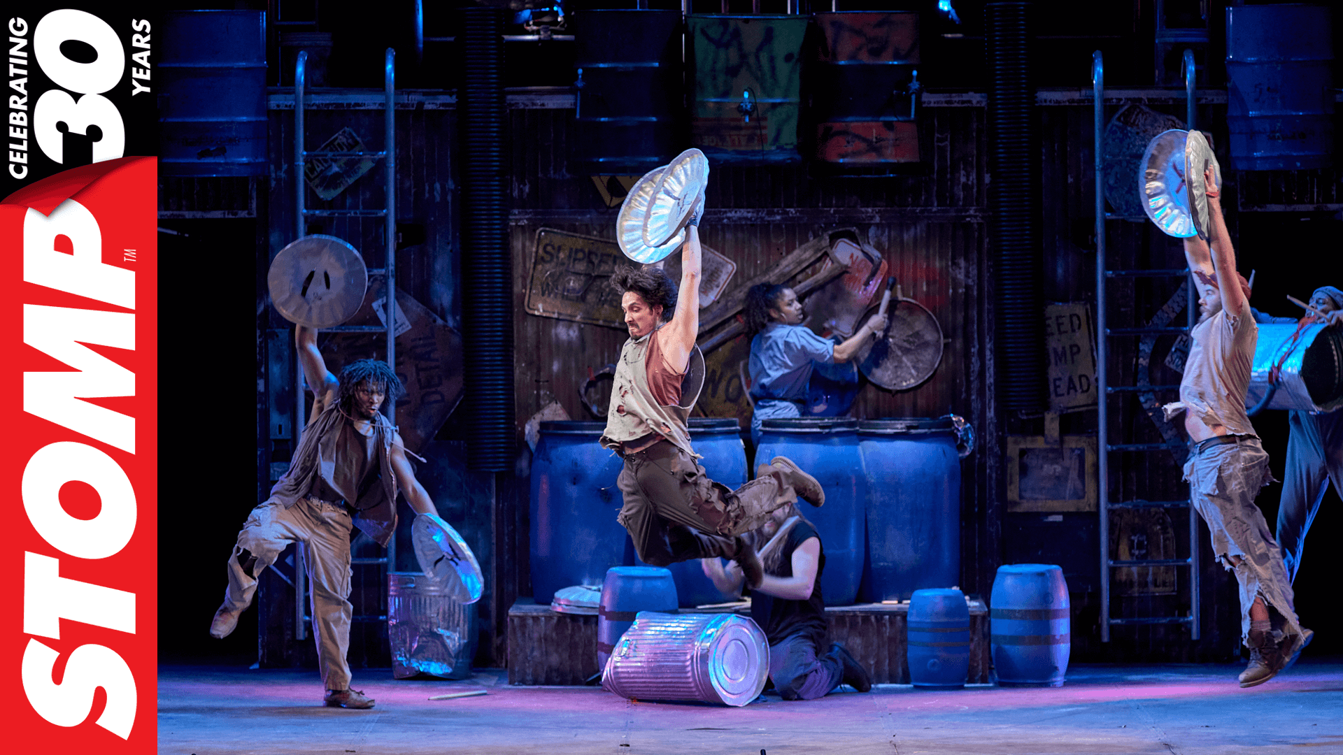 STOMP performers on stage with logo