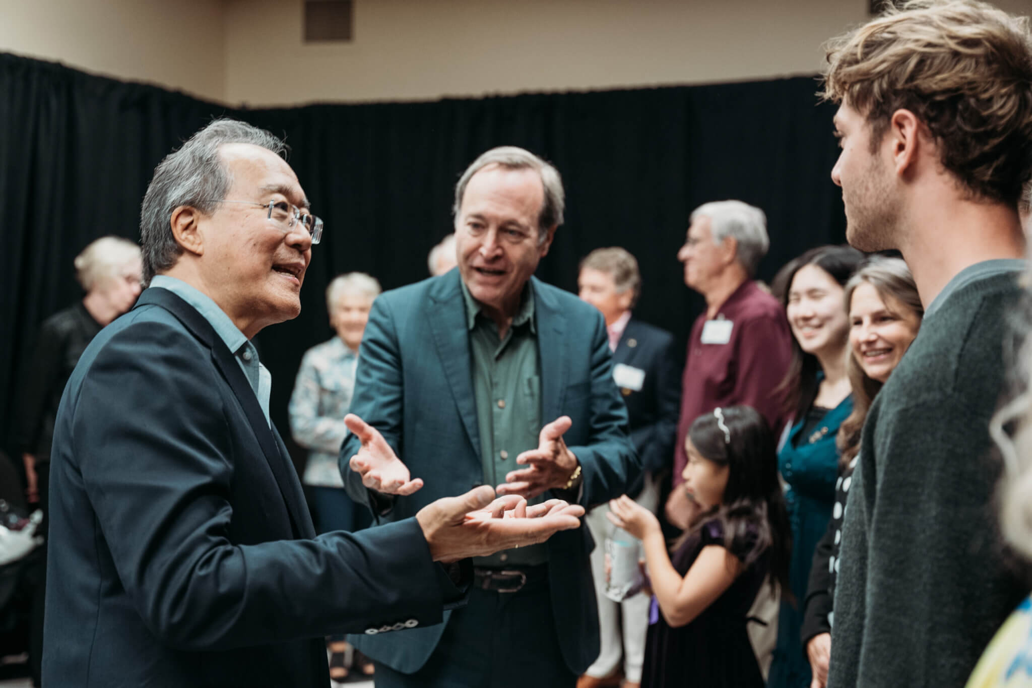 Cellist Yo-Yo Ma and journalist Jeffrey Brown speaking backstage with a Purdue student.