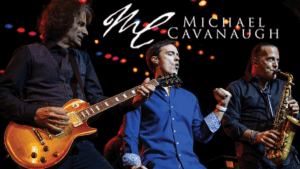 Three musicians perform passionately on stage under warm lights—one plays electric guitar, another sings into a microphone, and the third plays saxophone. The text Michael Cavanaugh, famed for his Billy Joel performances, is displayed above them.