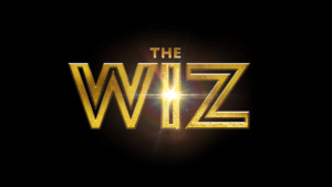 The words THE WIZ appear in large, bold, gold letters on a black background, with a bright light shining through the letter I in WIZ.