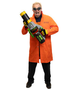 A person wearing black goggles, an orange lab coat, black pants, and gloves holds a large, toy-like gadget that resembles a futuristic blaster. The background is white.